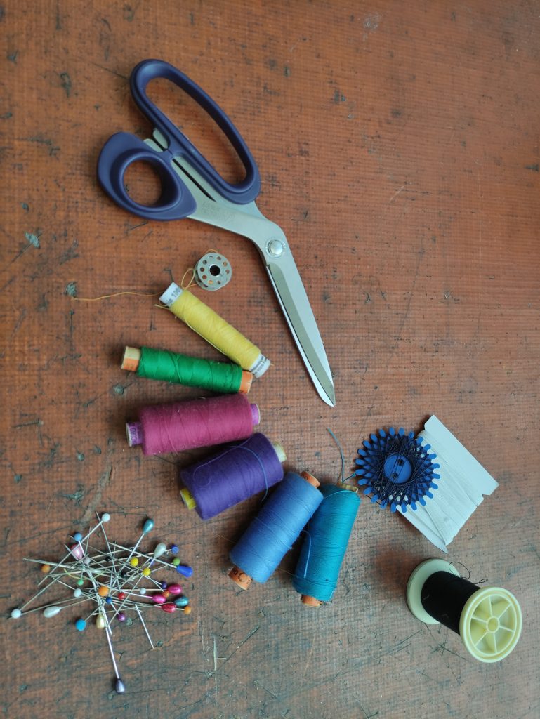ls-38-kalender--textiles-repair-cafe Eine Schere, bunte Garn-Rollen und Steck-Nadeln